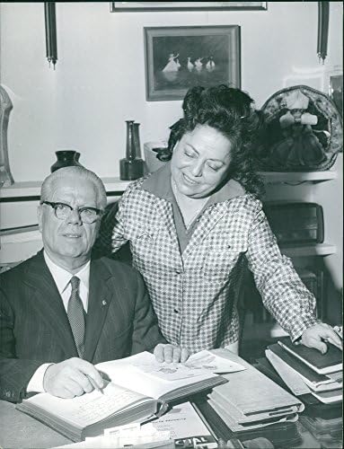 Foto vintage do homem sentado e olhando para a câmera, mulher em pé com ele. Photo tirado em 1963
