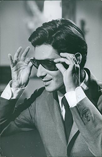 Foto vintage de Sami Frey verificando novos óculos de sol.