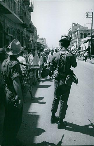Foto vintage de oficiais observando na rua.