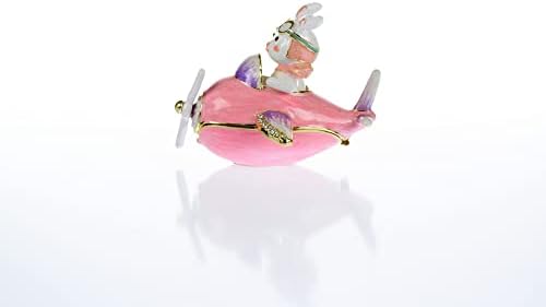 Keren Kopal Bunny pilotando uma caixa de bugigangas de avião rosa decorada com cristais para armazenamento de jóias.